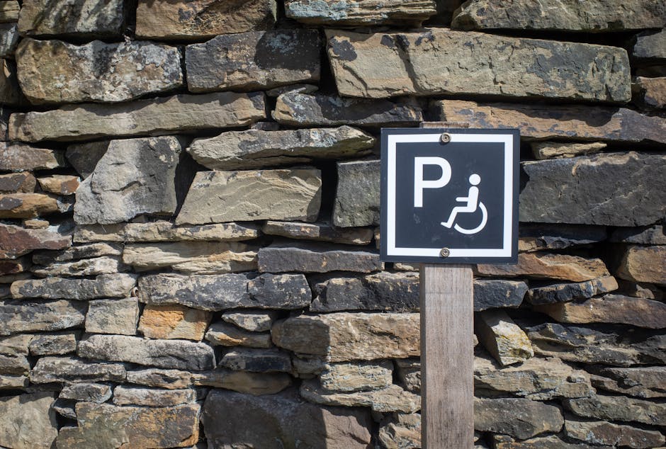 Outdoor accessible parking sign mounted on a rustic stone wall, sunny day.