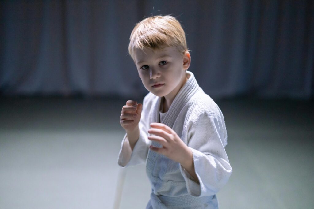 A young boy practicing martial arts indoors, focused and ready for action.